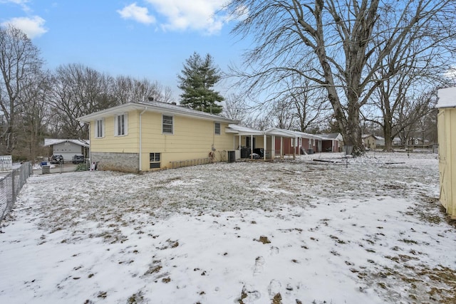 snow covered property featuring fence and central air condition unit