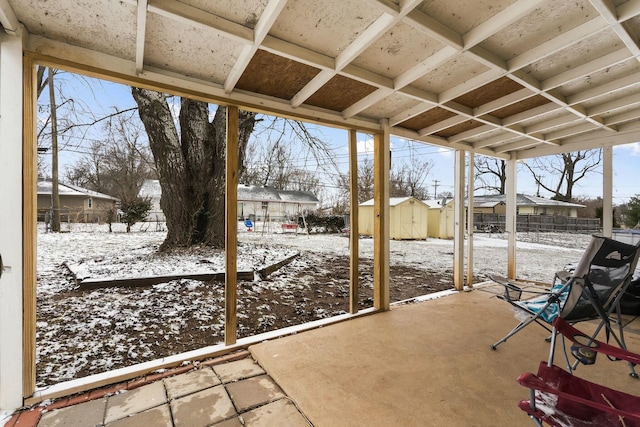 snow covered patio with a storage shed, a fenced backyard, and an outbuilding