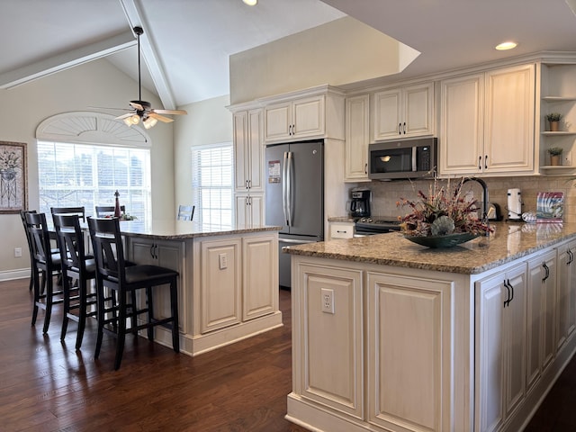 kitchen with dark wood-style floors, open shelves, appliances with stainless steel finishes, vaulted ceiling, and a kitchen bar