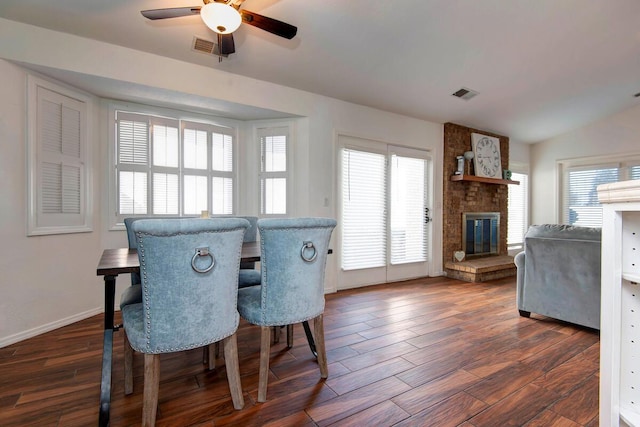 dining space with dark wood-style floors, a brick fireplace, and visible vents