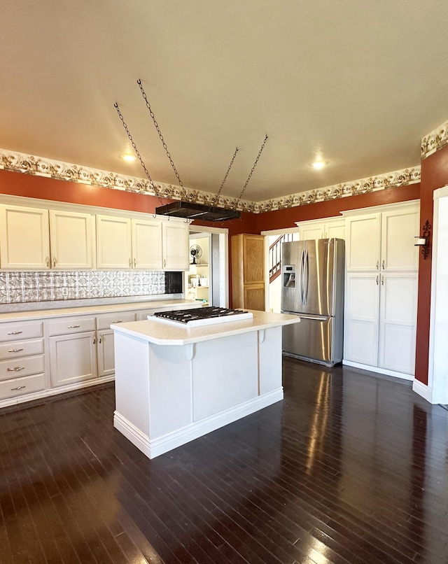 kitchen featuring stainless steel refrigerator with ice dispenser, white gas stovetop, light countertops, white cabinets, and a kitchen island