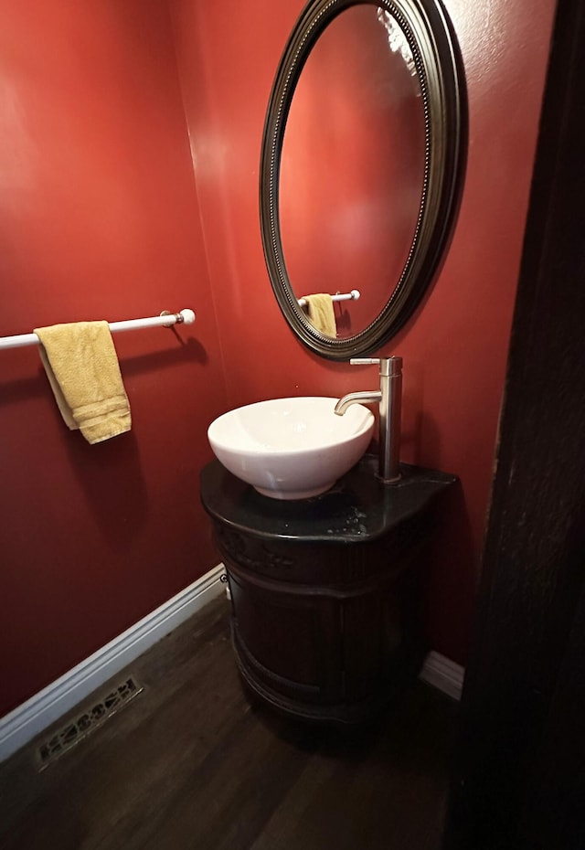 bathroom with wood finished floors, a sink, visible vents, and baseboards