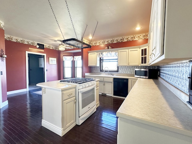 kitchen with black dishwasher, dark wood finished floors, gas range gas stove, light countertops, and stainless steel microwave