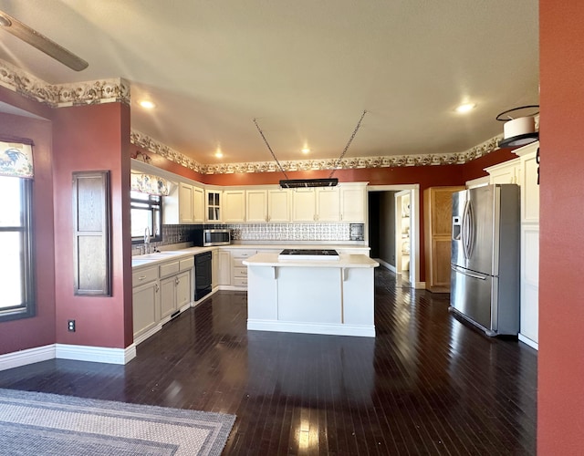 kitchen with dark wood-style flooring, stainless steel appliances, tasteful backsplash, light countertops, and a sink