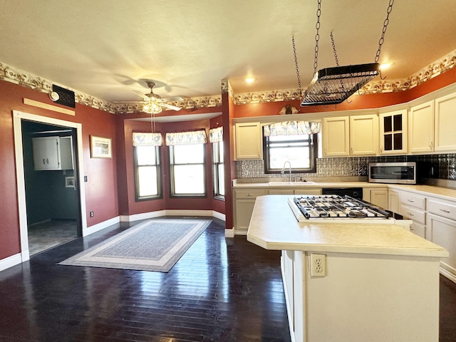 kitchen with appliances with stainless steel finishes, light countertops, a sink, and backsplash