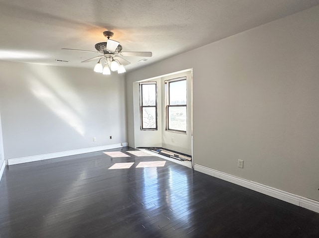 spare room featuring a ceiling fan, dark wood finished floors, a textured ceiling, and baseboards