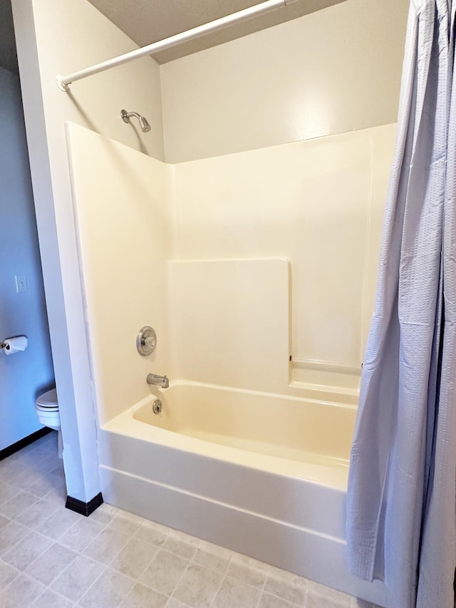 bathroom with toilet, shower / bathtub combination with curtain, baseboards, and tile patterned floors