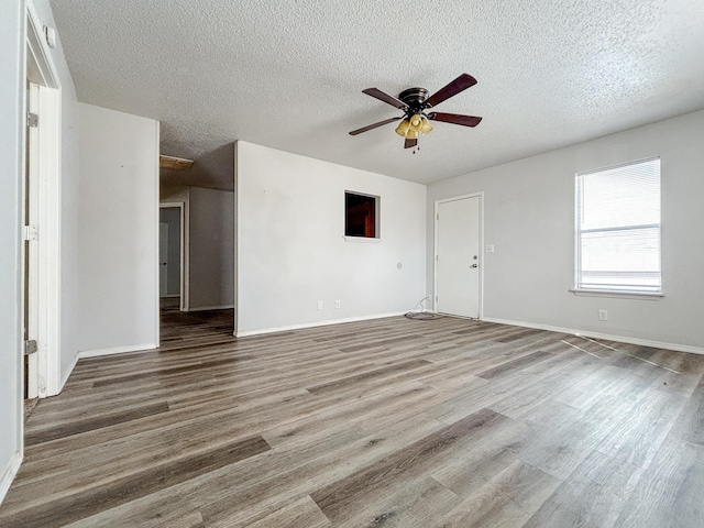 908 Jefferson Ave, Joplin, MO 64801 - unfurnished living room featuring ceiling fan, a textured ceiling, baseboards, and wood finished floors