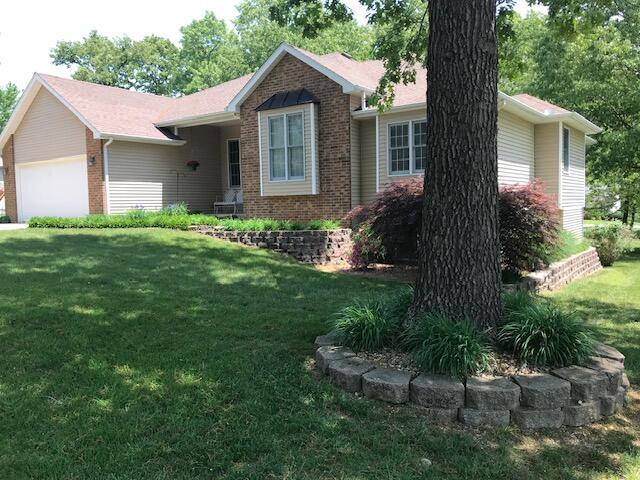 single story home featuring an attached garage, a front yard, and brick siding