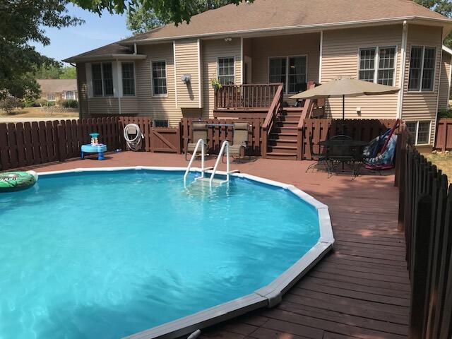 view of pool featuring a fenced in pool, stairs, fence, a deck, and outdoor dining space