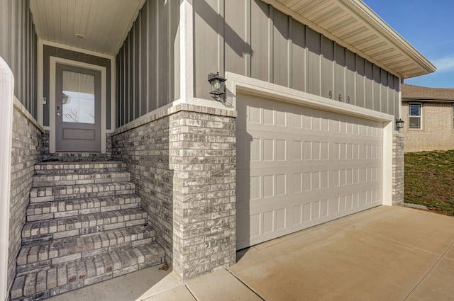 doorway to property with board and batten siding, brick siding, and driveway