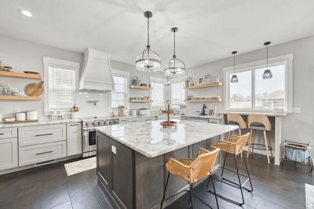 kitchen with dark wood finished floors, custom range hood, a kitchen island, stainless steel range with electric cooktop, and open shelves