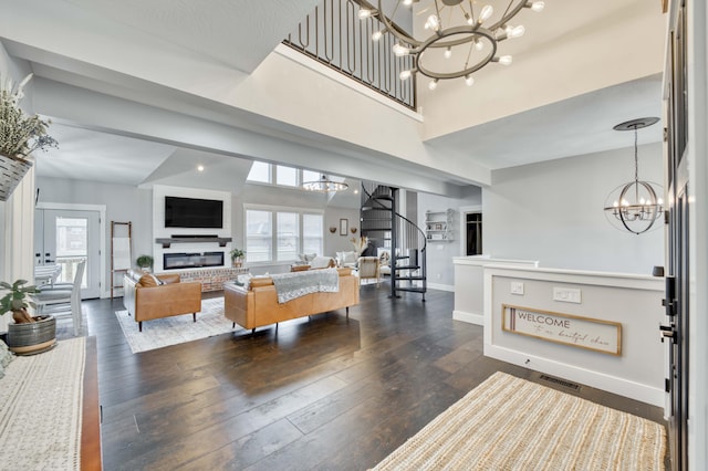 living area with baseboards, a glass covered fireplace, dark wood finished floors, and a notable chandelier