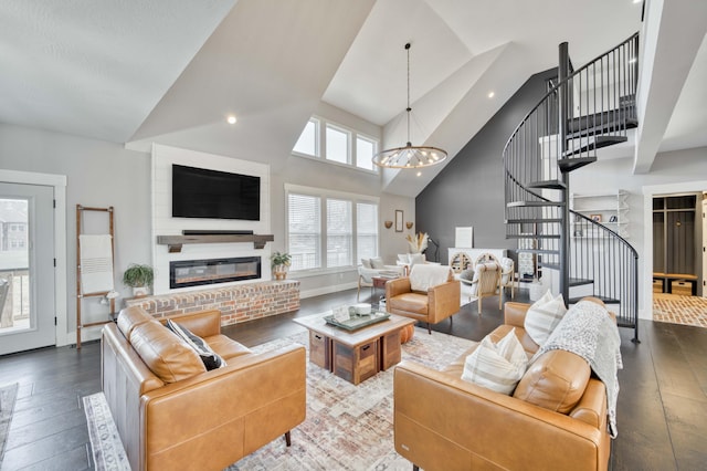 living room with a chandelier, a glass covered fireplace, hardwood / wood-style floors, and stairs