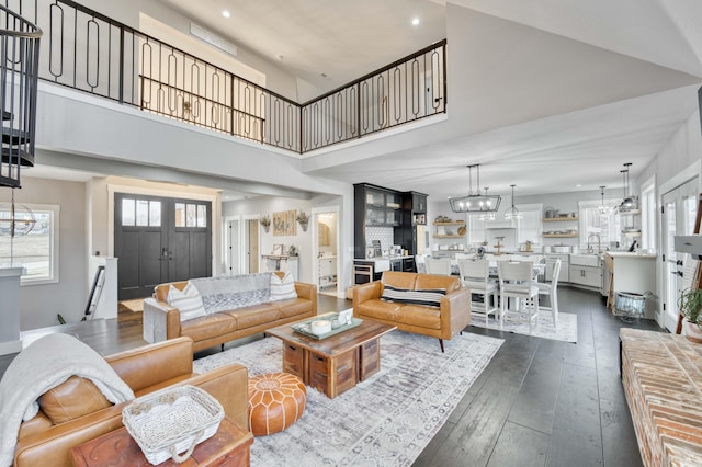 living room featuring recessed lighting, a notable chandelier, a high ceiling, french doors, and dark wood-style floors