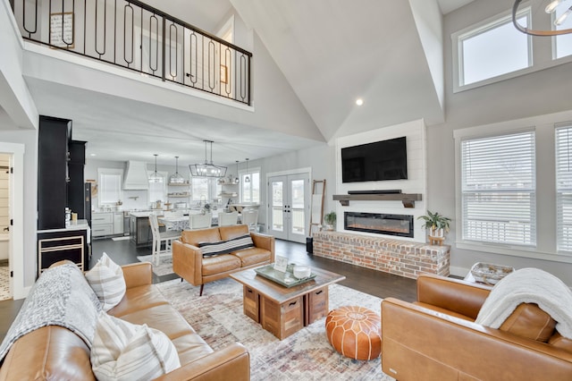 living room featuring french doors, a fireplace, a high ceiling, and wood finished floors