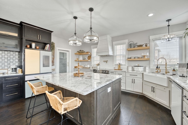 kitchen with a kitchen island, stove, premium range hood, open shelves, and a sink