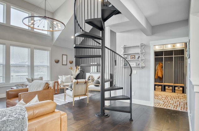 interior space featuring a towering ceiling, hardwood / wood-style flooring, baseboards, and a notable chandelier