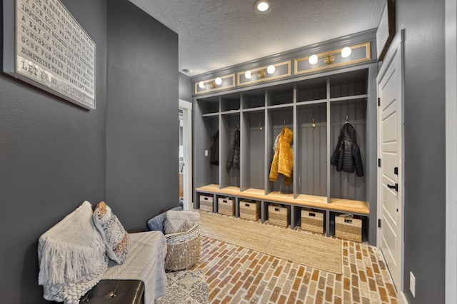 mudroom with a textured ceiling and brick floor