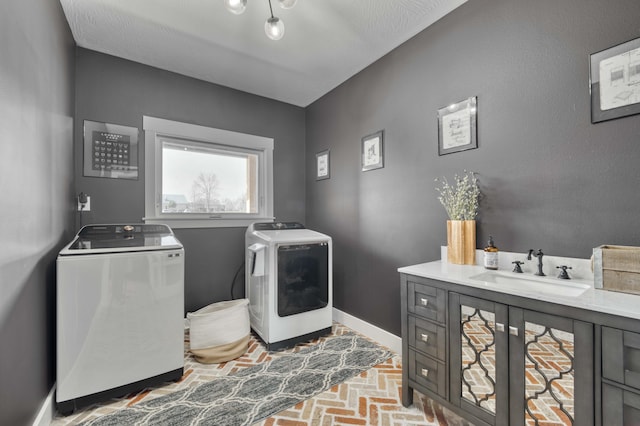 laundry room with brick floor, a sink, separate washer and dryer, laundry area, and baseboards