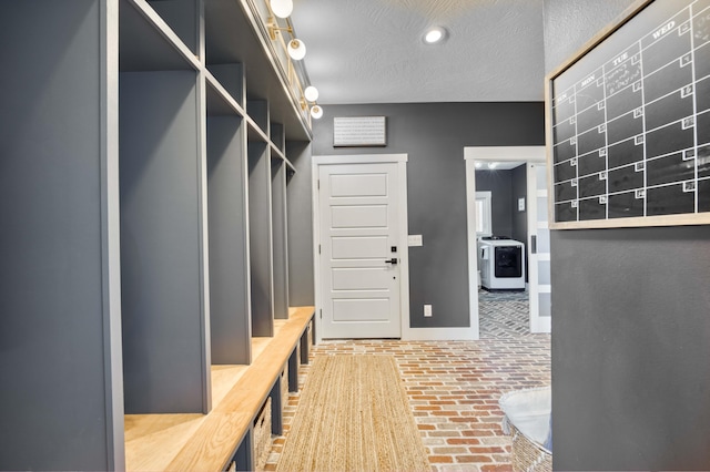 mudroom with brick floor, baseboards, washer / clothes dryer, and a textured ceiling