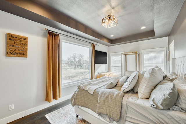 bedroom with baseboards, a raised ceiling, dark wood finished floors, a textured ceiling, and recessed lighting