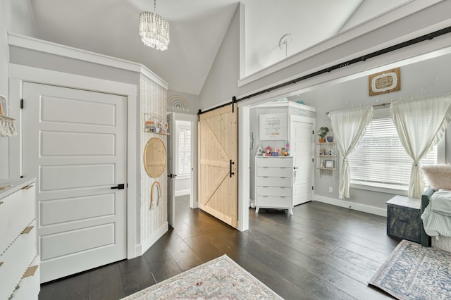 entrance foyer with lofted ceiling, a chandelier, a barn door, dark wood-type flooring, and baseboards