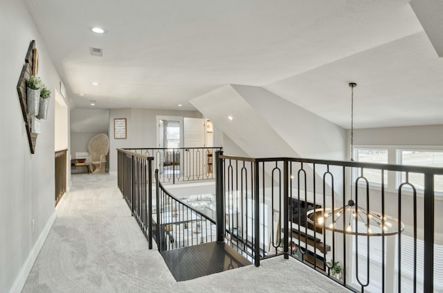 hallway featuring an inviting chandelier, visible vents, carpet flooring, and an upstairs landing