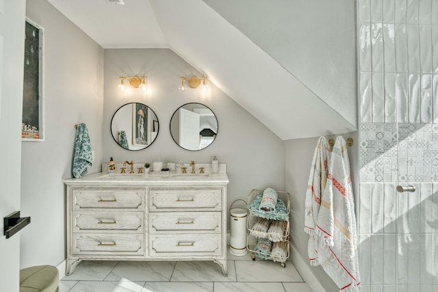 bathroom with marble finish floor, vaulted ceiling, a sink, and double vanity