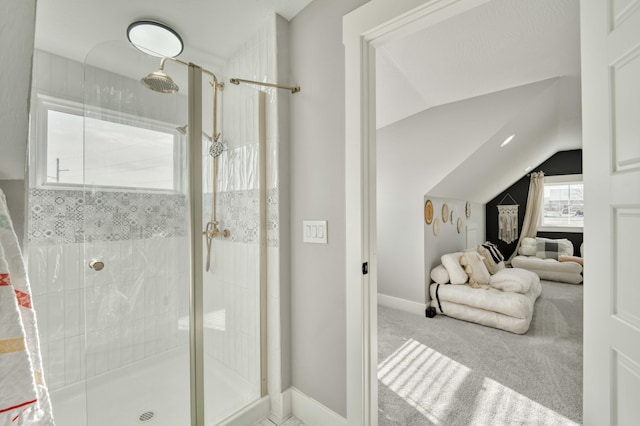 bathroom featuring a stall shower, vaulted ceiling, and baseboards