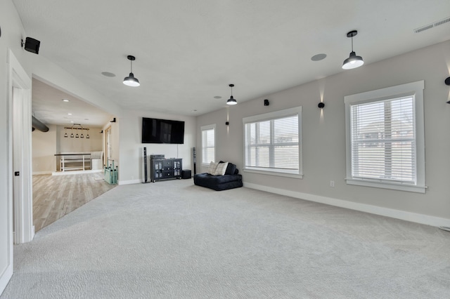 unfurnished living room featuring light carpet, visible vents, and baseboards