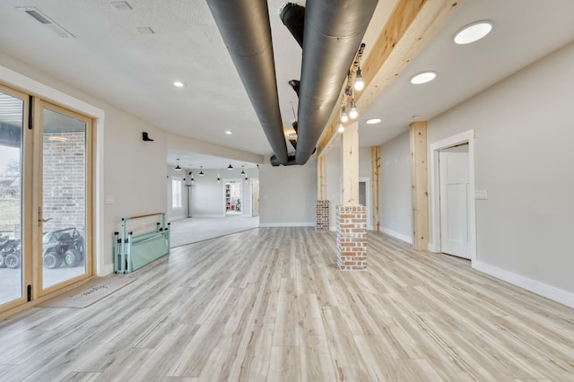 unfurnished living room featuring light wood finished floors, visible vents, and baseboards