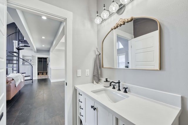 bathroom with hardwood / wood-style flooring, vanity, baseboards, and recessed lighting