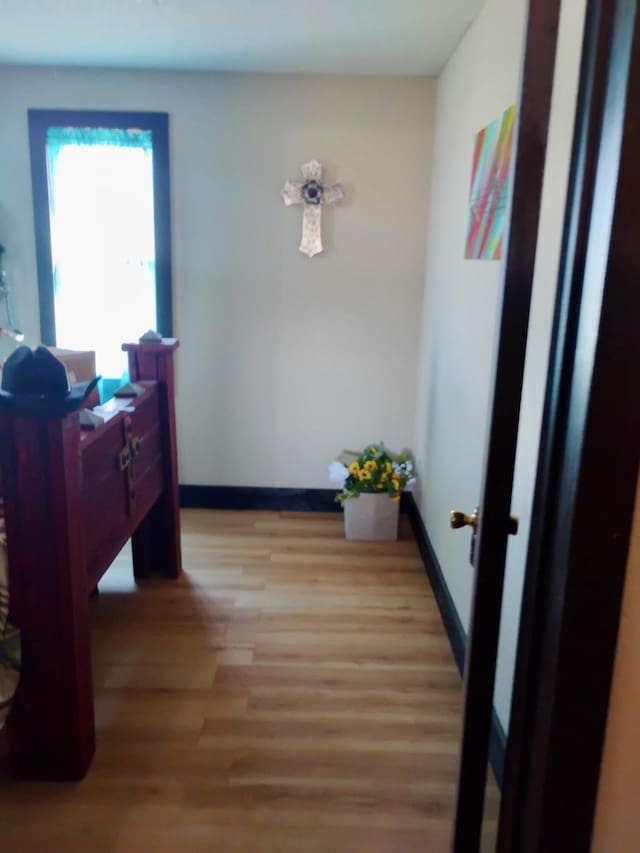 corridor featuring light wood-style floors and baseboards