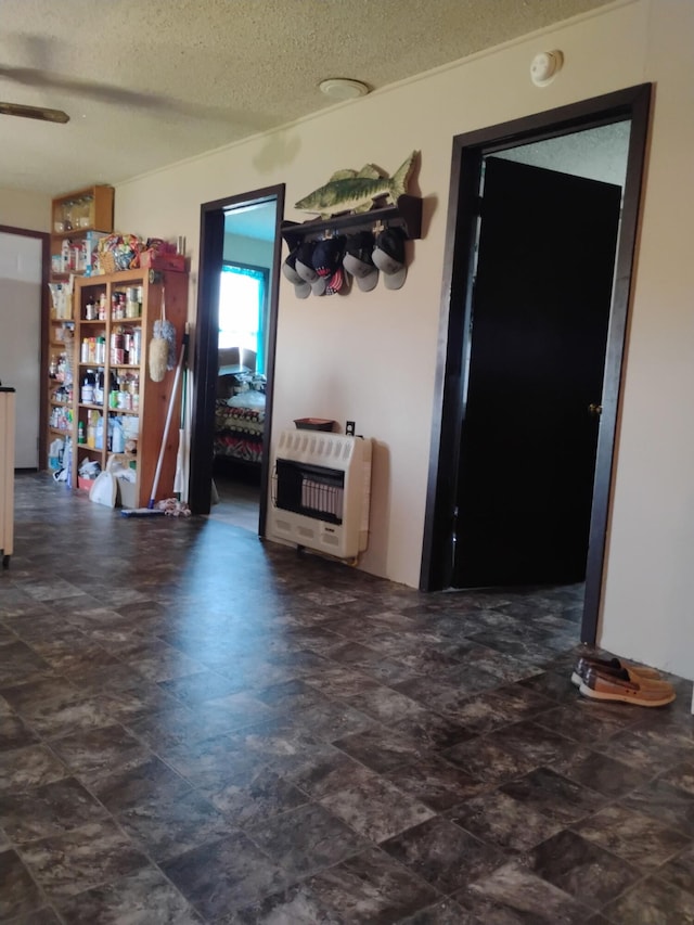 interior space featuring a textured ceiling, ceiling fan, and heating unit
