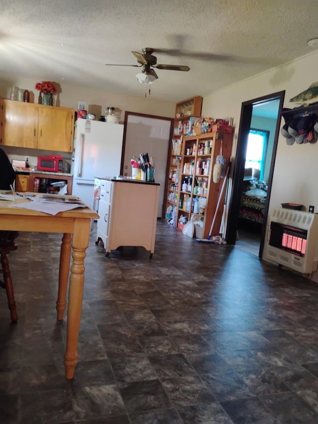 kitchen featuring a ceiling fan, freestanding refrigerator, heating unit, and a textured ceiling