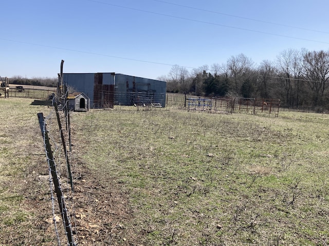 view of yard with an outbuilding, fence, and a rural view