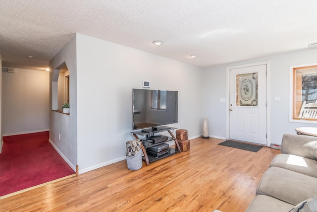 living area with a textured ceiling, wood finished floors, and baseboards