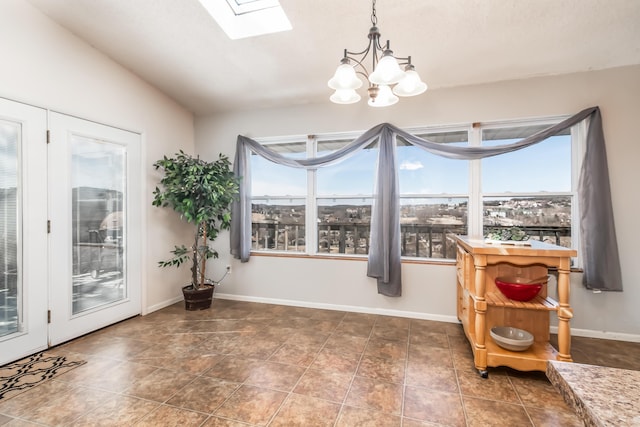 dining space with a chandelier, a skylight, a wealth of natural light, and baseboards