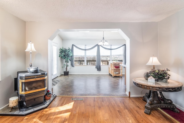 interior space featuring a wood stove, an inviting chandelier, baseboards, and wood finished floors