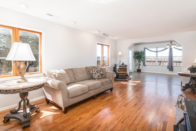 living room with visible vents, baseboards, light wood-style flooring, a wood stove, and a chandelier