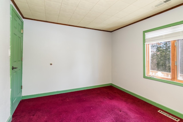 empty room with dark colored carpet, ornamental molding, and visible vents