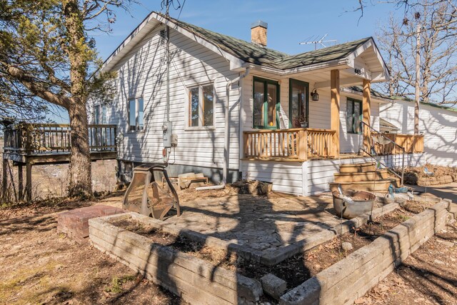 view of property exterior with covered porch and a chimney