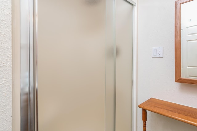 bathroom with a textured wall and a stall shower