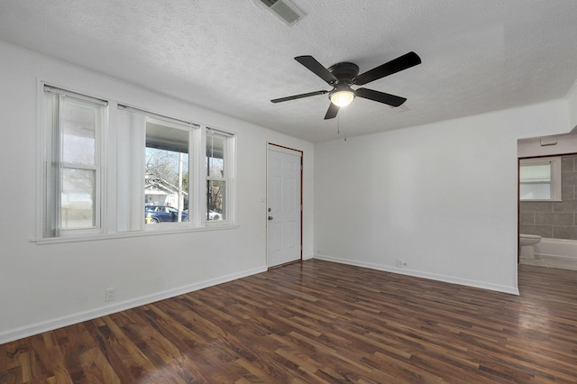 empty room with a textured ceiling, dark wood-style flooring, and visible vents