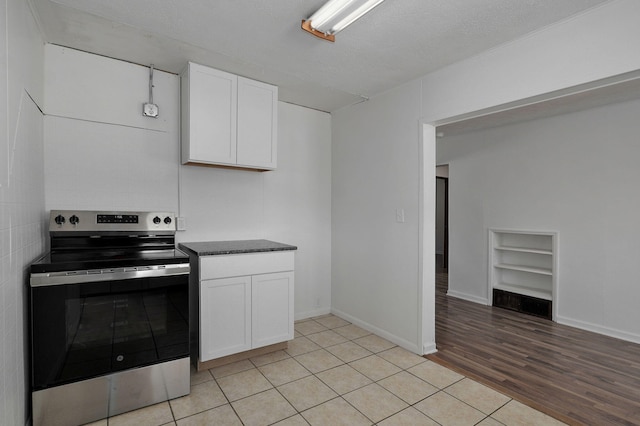 kitchen with built in features, light wood finished floors, stainless steel electric stove, white cabinetry, and baseboards