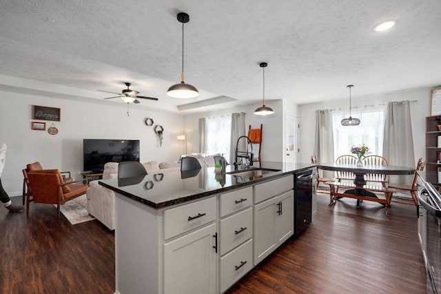 kitchen with dark wood-style floors, pendant lighting, a raised ceiling, a sink, and a textured ceiling