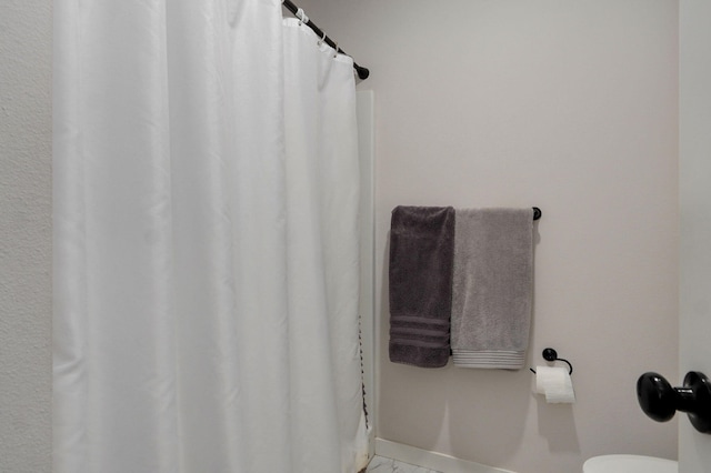 bathroom featuring marble finish floor, toilet, and baseboards
