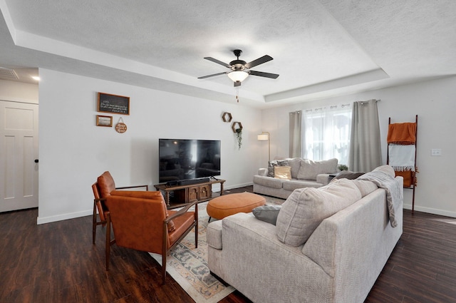 living area featuring baseboards, a textured ceiling, a tray ceiling, and wood finished floors