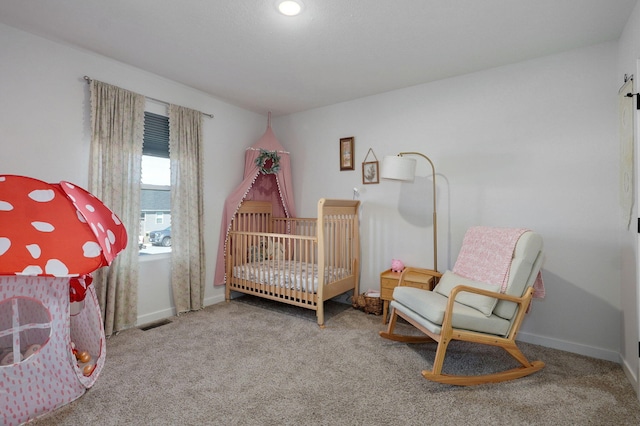 bedroom featuring a nursery area, carpet floors, visible vents, and baseboards